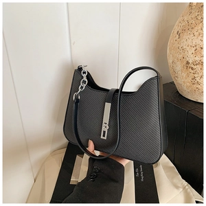 Détail du sac sous l'aisselle en cuir noir texturé avec boucle argentée et petite chaîne