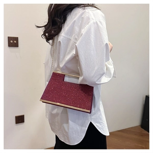 Dettaglio di una borsa da sera bordeaux con paillettes indossata a spalla da una modella