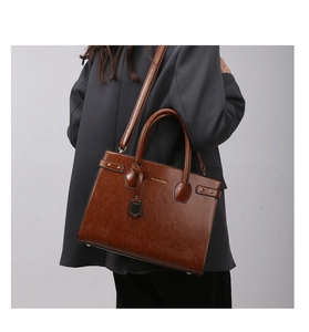 Detailed view of brown leather tote bag texture with gold studs and adjustable shoulder strap