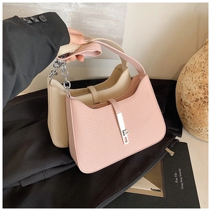 Gros plan sur la texture tressée et la boucle argentée d'un sac hobo rose chic