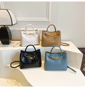 Detailed display of four crocodile embossed handbags with woven straps and bow hardware