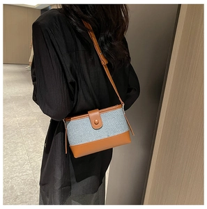 Detail of blue tweed and brown leather patchwork shoulder bag worn on a model