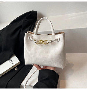 Detailed shot of white faux crocodile texture and elegant gold knot buckle on handbag