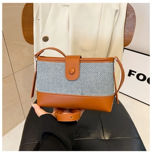 Detail of blue denim and brown leather contrast stitching on a retro crossbody bag