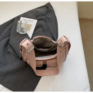 Pink underarm bag with matte leather finish and dual front utility pockets shown in setting