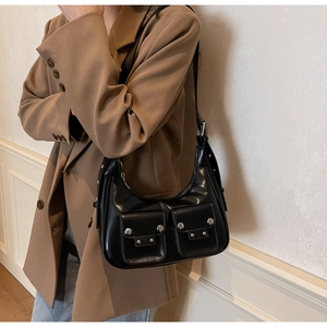 Detailed close-up of a black crescent underarm bag with silver rivets and dual flap pockets