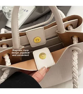 Close-up of magnetic snap closure and crocodile texture on beige tote handbag
