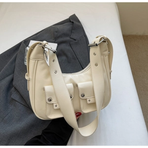 Detail of off-white hobo bag with flap pockets and silver buckles on a grey suit