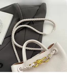 Close-up of white crocodile pattern tote bag with woven strap and gold metal buckle