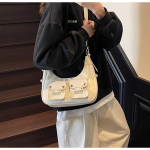 Close-up of white patent leather shoulder bag with silver studs and buckle pocket detail