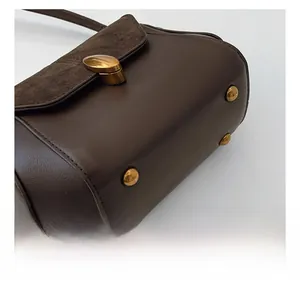 Detailed close-up of dark brown crossbody bag with gold protective feet and smooth leather