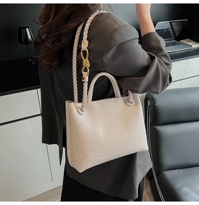 Detail of cream crocodile pattern tote bag with woven strap and gold knot buckle