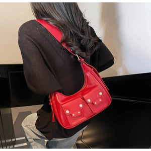 Close-up of bright red glossy shoulder bag with dual front pockets and silver stud details