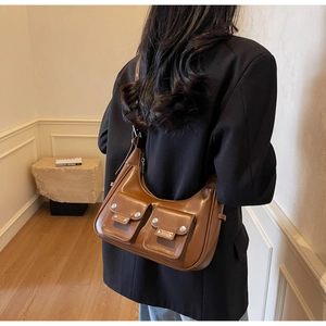 Detail of a brown leather shoulder bag with silver rivets and double front flap pockets