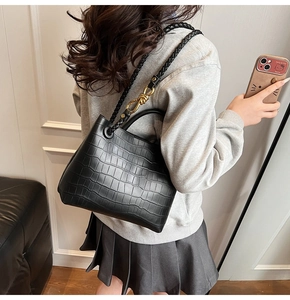 Side view of black crocodile pattern tote bag with woven strap shown on model