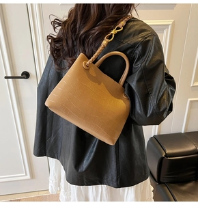 Brown crocodile embossed handbag with a woven shoulder strap shown on a model
