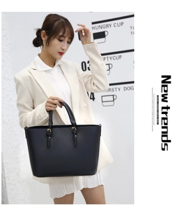 Detail of a black matte leather tote bag featuring gold hardware and elegant double handles