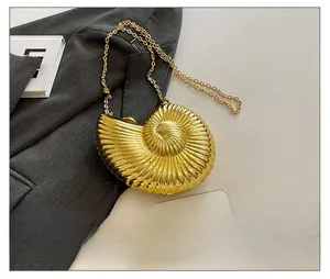 Close-up of golden shell-shaped acrylic evening bag on grey blazer with chain strap