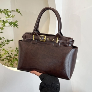 Borsa tote vintage marrone scuro con fibbia dorata in un ambiente minimalista