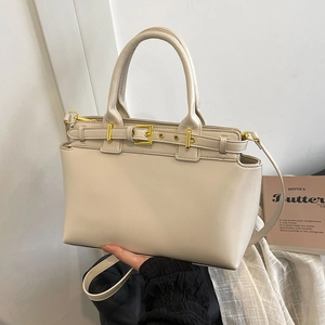 Elegante borsa tote in pelle crema con finiture dorate su uno sfondo minimalista
