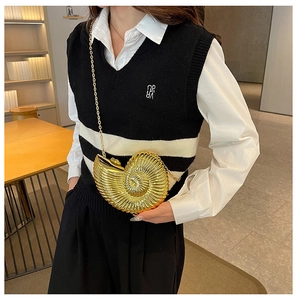 Detailed view of the gold seashell-shaped acrylic clutch with metallic chain strap