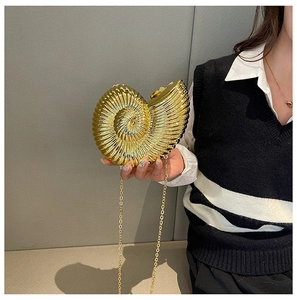 Detailed view of a gold nautilus shell clutch bag with a high-shine metallic finish and chain