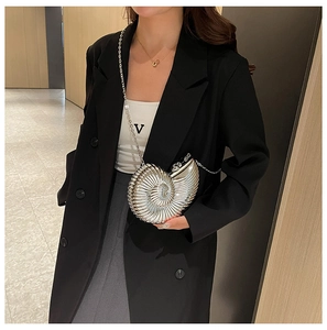 Detail of silver metallic shell bag with spiral texture and chain on black blazer background