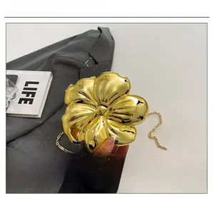 Macro detail of gold flower-shaped metal clutch with layered petals and chain