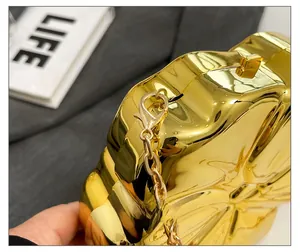 Detailed view of golden acrylic handbag with wave relief and high-shine metallic chain