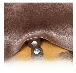 Detailed macro view of the premium magnetic snap fastener on the brown leather bag