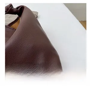 Close-up of deep brown lychee texture leather bag featuring knot detail and suede lining