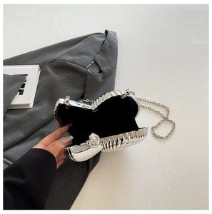 Detail view of the silver shell-shaped acrylic bag with a metal chain and velvet lining