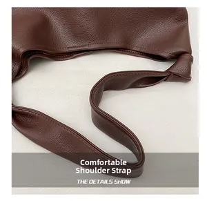 Detail of wide knotted shoulder strap on brown leather tote bag with grainy texture