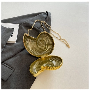 Macro detail of golden nautilus shell clutch with metallic chain on a grey blazer