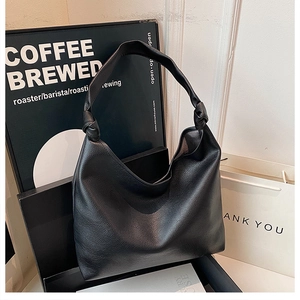 Detailed shot of black lychee grain faux leather hobo bag with unique knotted strap design
