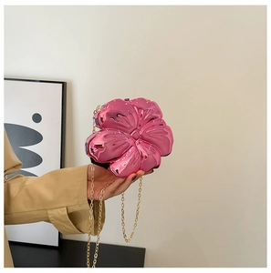 Detail of a pink floral acrylic clutch with a polished metallic finish and gold chain strap