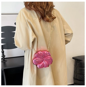 Detail shot of a mini pink flower-shaped bag with a metallic finish and gold chain strap