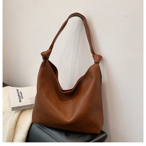 Detail of a brown leather Hobo bag featuring a knotted strap and lychee texture