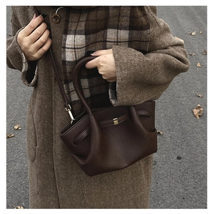 Dettaglio della borsa in pelle testa di moro con fibbia dorata portata da modella in cappotto