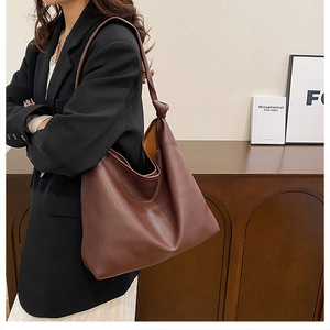 Detail of a large brown hobo bag featuring a decorative knotted strap and leather texture