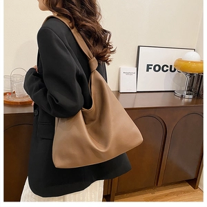 Brown litchi texture tote bag with knot handle detail worn with a casual city outfit