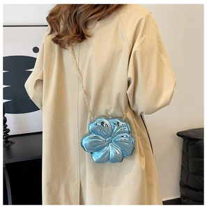 Detail of blue flower chain bag with glossy metallic finish on a beige trench coat