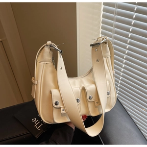 Chic beige underarm bag with silver rivets and double front pockets on black surface