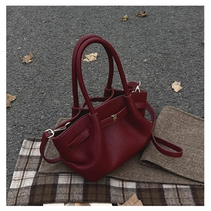 Dettaglio borsa a secchiello bordeaux vintage con pelle martellata e fibbie dorate