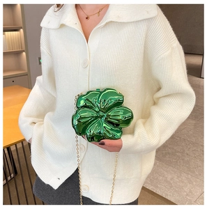 Detail of green acrylic flower evening bag with glossy finish and gold chain strap