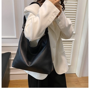 Detail of black pebbled leather tote bag featuring a decorative knot on the shoulder strap