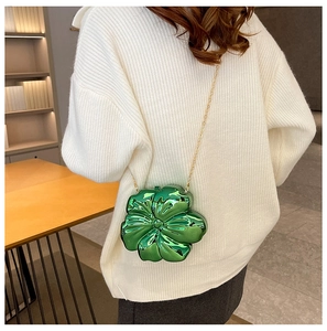 Detail of green floral acrylic handbag with metallic finish and gold chain on model