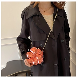 Detail of rose gold flower-shaped acrylic clutch with metallic chain on model