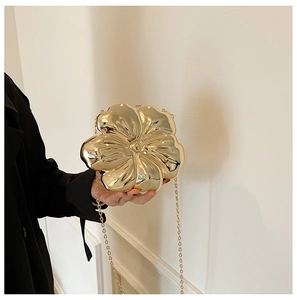 Detailed view of flower-shaped gold metal evening clutch with polished mirror finish