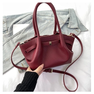 Dettaglio della borsa in pelle bordeaux con design ad ali e tracolla rimovibile